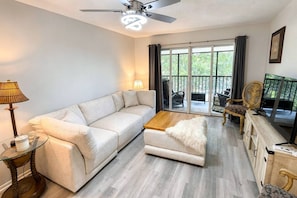 A modern living room with a sofa, coffee table, and a television. - Renovated Condo Across from Siesta Key Beach | (Siesta Key)