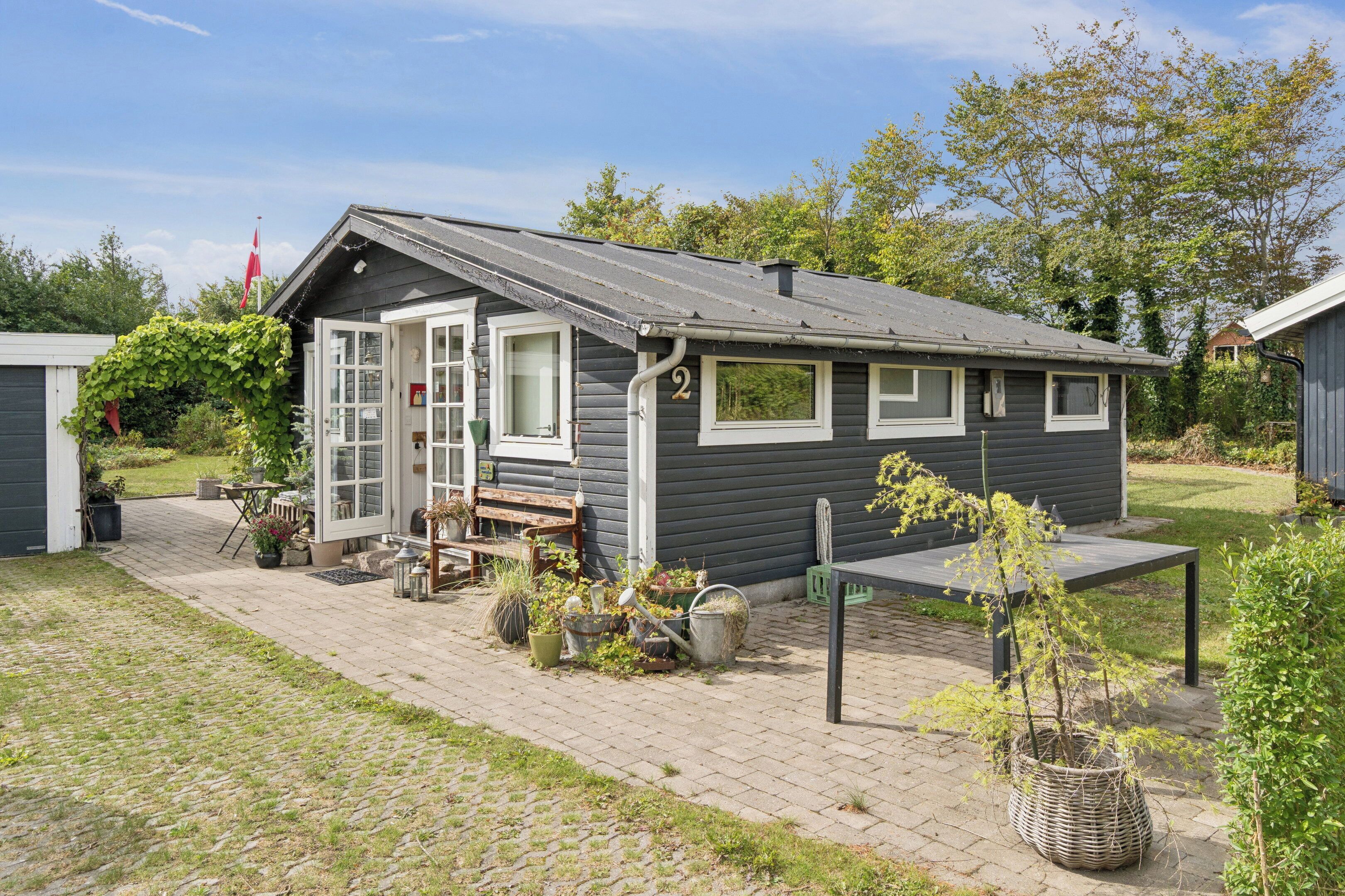 A small, single-story cabin with a door, windows, and a bench outside.