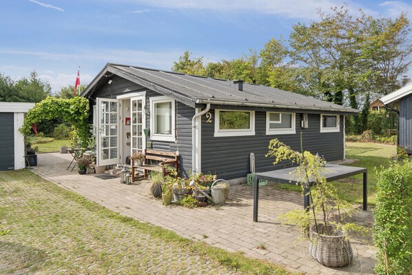 A small, single-story cabin with a door, windows, and a bench outside.