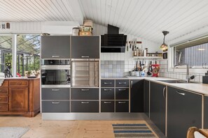 A modern kitchen with a large island, built-in appliances, and a view through the window.
