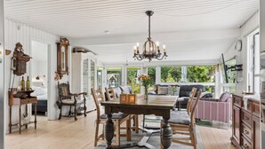Un coin repas avec une table et des chaises en bois, un lustre et une vue sur l’extérieur.