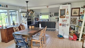 A spacious kitchen with a dining area, wooden flooring, and a view through large windows.