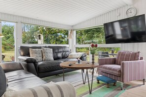 A modern living room with a black leather sofa, a striped armchair, and a round wooden coffee table. - Cozy house by Klitgård Fishing Village (Nibe)