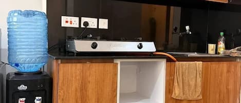 Una cocina con armarios de madera, una estufa a gas, un dispensador de agua y una toalla colgada en la encimera.