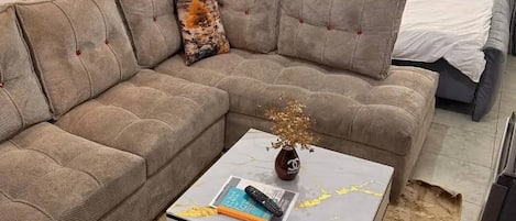 Una sala de estar moderna con un sofá modular, una mesa de centro y un cabecero gris capitonado.