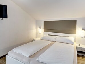 A hotel room with a bed, bedside tables, a flat-screen TV, and wall-mounted lights. - LoriVita by Interhome (Saalbach-Hinterglemm)