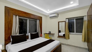 A hotel room with a large bed, a desk, an air conditioning unit, a mirror, and a wardrobe. - Premium Financial District Gachibowli Srinika (Hyderabad)