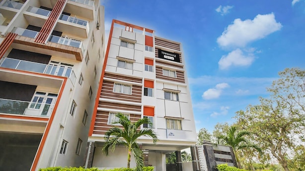 A multi-story residential building with a sign indicating 'TOWNHOUSE' and 'OYO-Serviced' amenities. - Premium Financial District Gachibowli Srinika (Hyderabad)