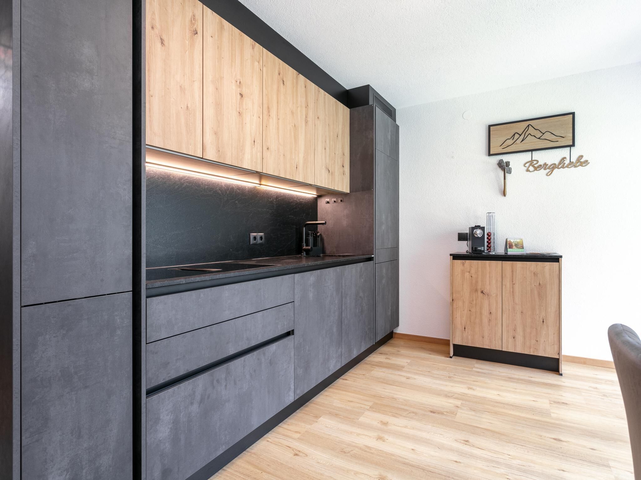 A modern kitchen with dark cabinetry, a wooden countertop, and a small wooden sideboard.