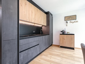 Una cocina moderna con armarios oscuros, una encimera de madera y un aparador pequeño de madera.