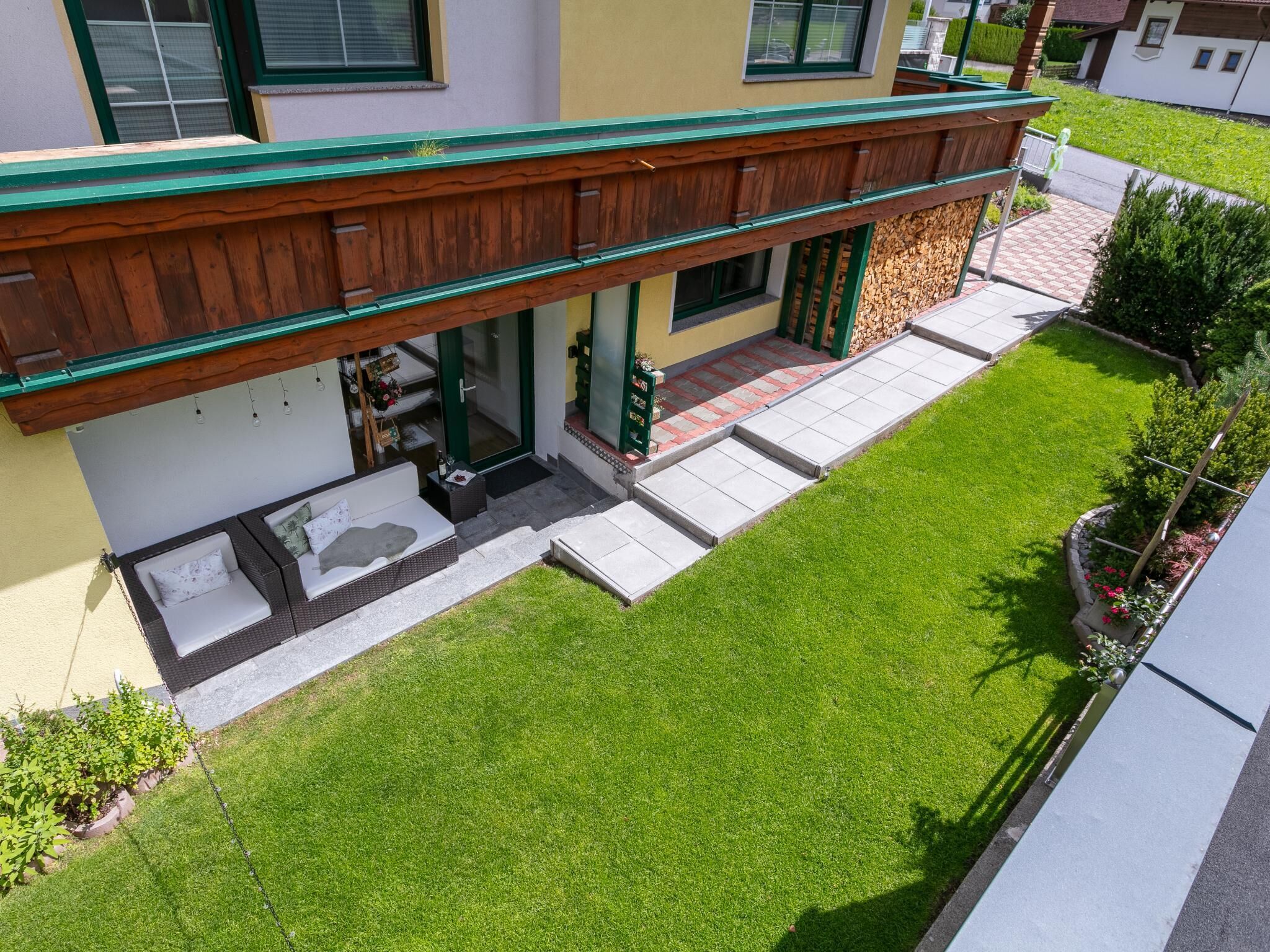 A two-story building with a covered porch, a small outdoor seating area, and a well-maintained lawn.
