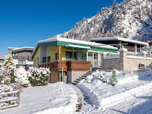 A modern building with a green roof, a wooden balcony, and a stone facade.