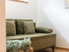 A sofa with multiple cushions against a plain wall.