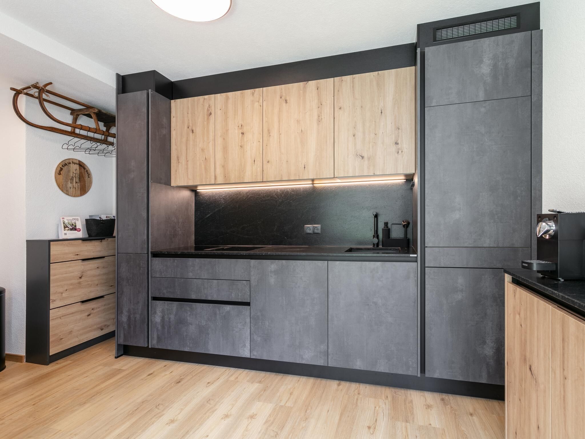 A modern kitchen with wooden cabinets, a black countertop, and a built-in oven.