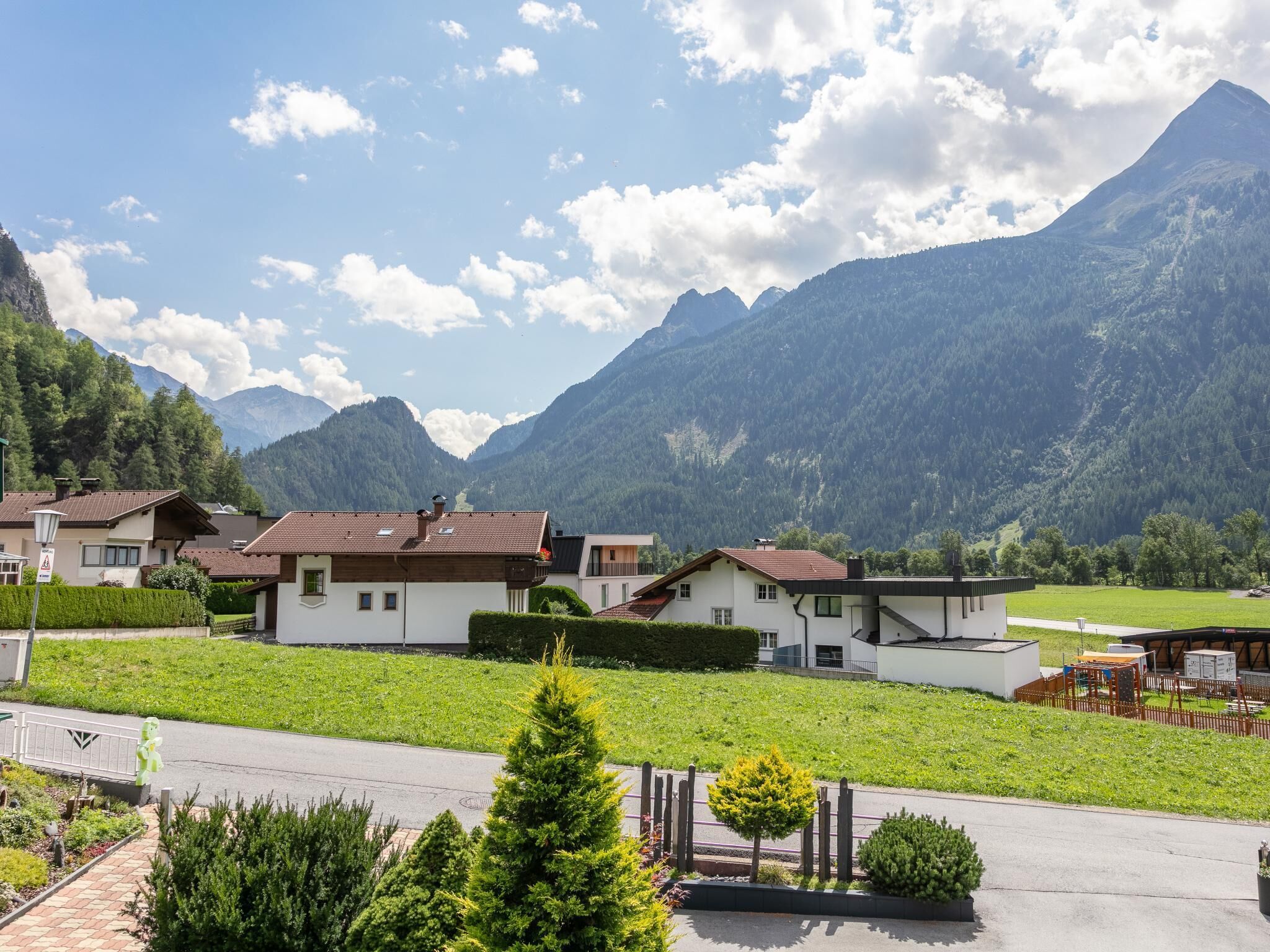 Ein Wohngebiet mit Häusern, einer befestigten Straße und Bergen im Hintergrund.