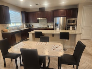 A modern kitchen with dark wood cabinets, stainless steel appliances, and a marble countertop.