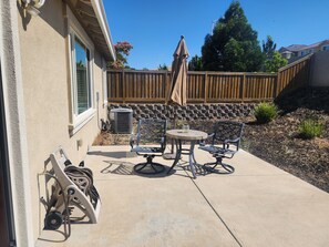A patio with a table and chairs, a wooden fence, and a stone wall. - Fantastic 4-bedroom house with AC in cool Bay Point (Bay point)