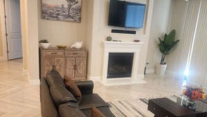 A living room with a sofa, a fireplace, a television, and a potted plant. - Fantastic 4-bedroom house with AC in cool Bay Point (Bay point)