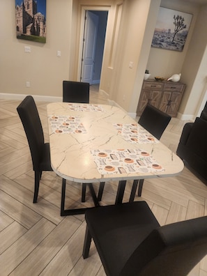 A dining area with a marble-patterned table, black chairs, and a wooden cabinet in the background.