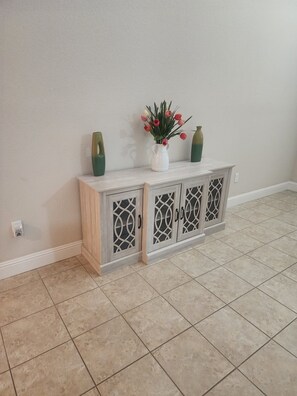 A corner with a light-colored tiled floor, a white wall, and a wooden cabinet with glass doors. - Fantastic 4-bedroom house with AC in cool Bay Point (Bay point)
