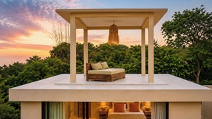 Un dormitorio moderno con cama bajo dosel, vista al cielo y follaje.