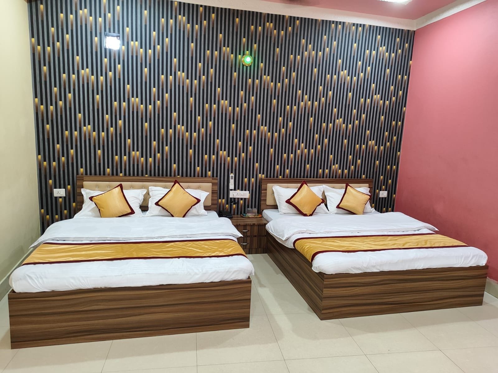 Cama doble con estructura de madera y ropa de cama blanca, dos mesitas de noche con lámparas y una pared con listones verticales e iluminación empotrada.