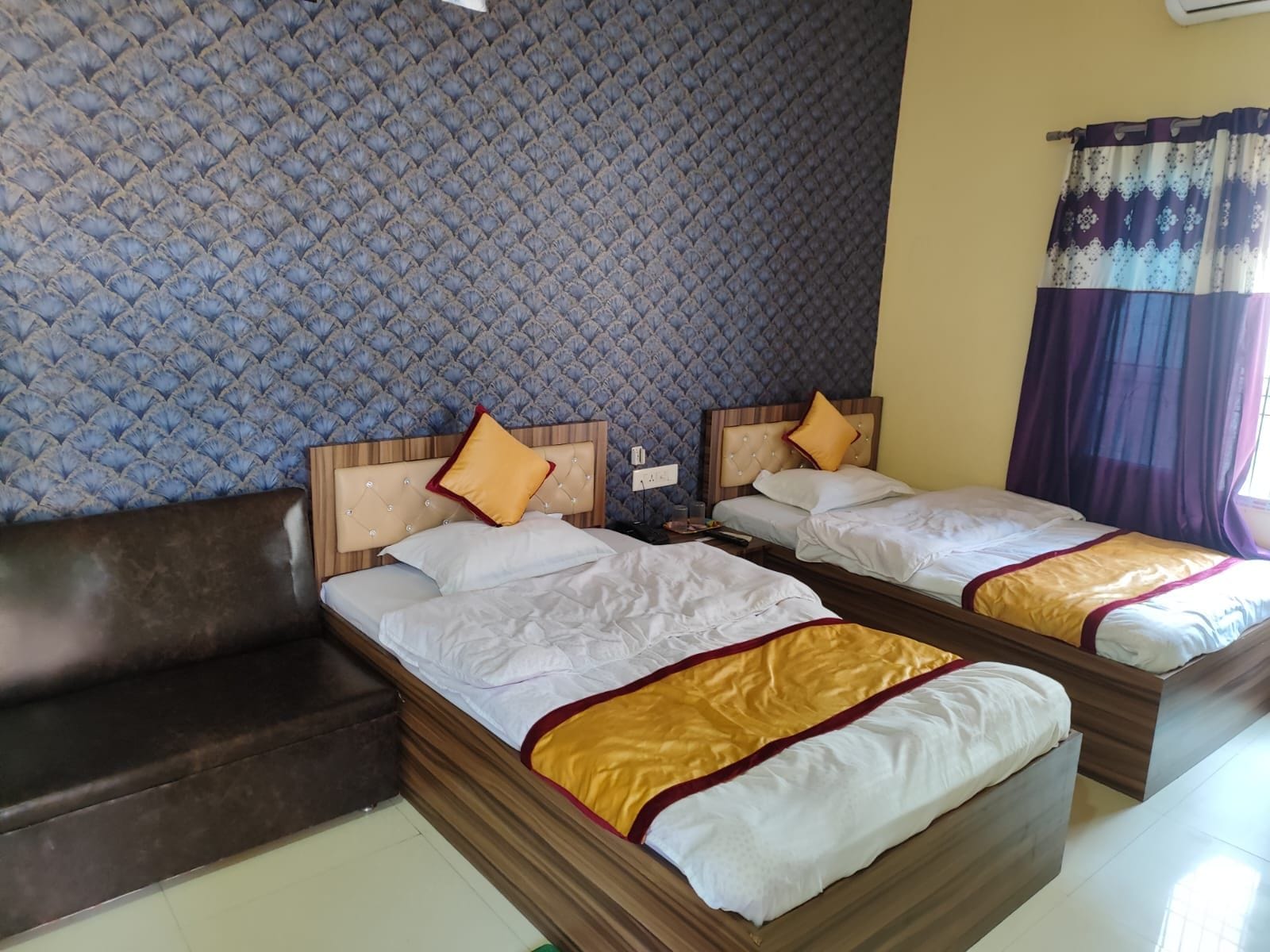 Habitación de hotel con dos camas, un sofá y una pared con estampado.