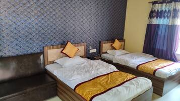 Habitación de hotel con dos camas, un sofá y una pared con estampado.