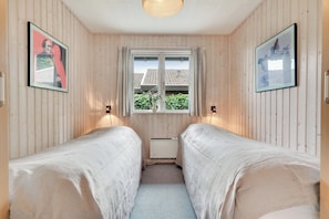 A room with two single beds, a window with curtains, and two wall-mounted lamps. - Stunning Sea Views, Wood-Fired Hot Tub & Nature (Haarby)