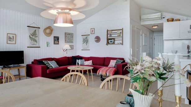 A modern living room with a red sofa, wooden dining table, and a TV. - Stunning Sea Views, Wood-Fired Hot Tub & Nature (Haarby)