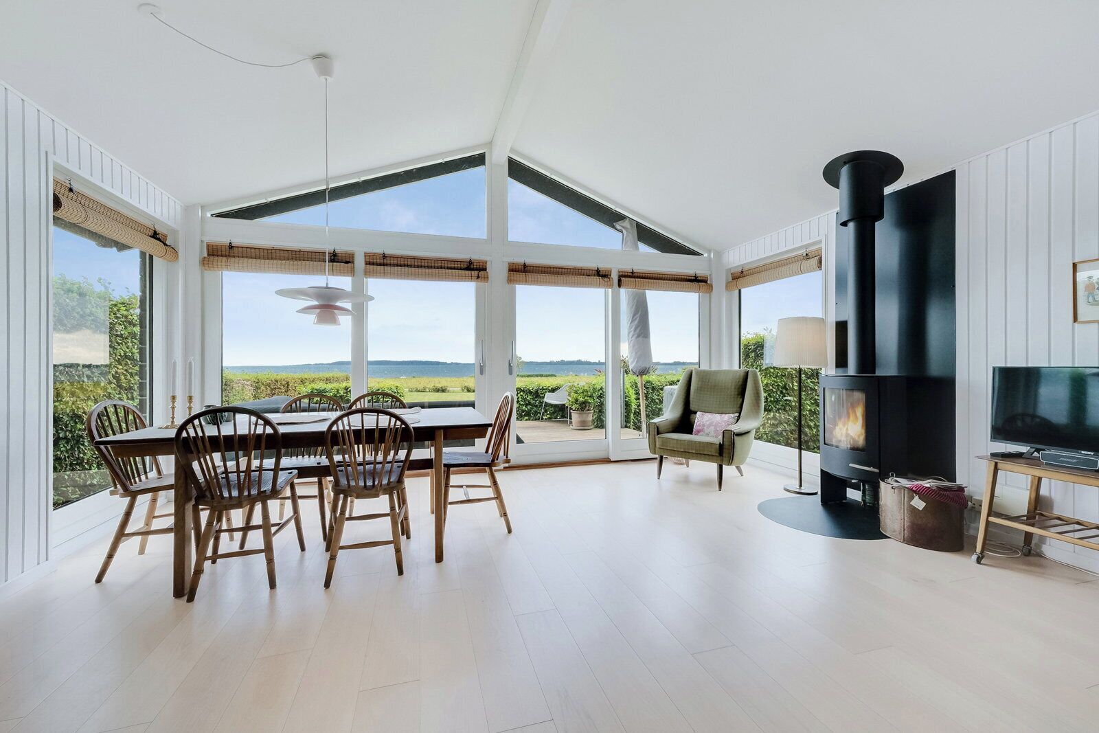 A spacious room with a large dining table, chairs, a sofa, a TV, and a fireplace.