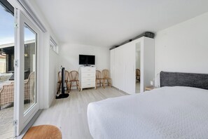 Ein Schlafzimmer mit einem Bett, einem Fernseher, einem Schreibtisch und Stühlen.