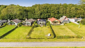 A residential area with houses, a road, and a forested hill in the background. - Stunning Sea Views, Wood-Fired Hot Tub & Nature (Haarby)