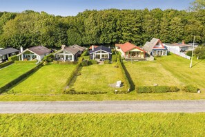A residential area with houses, a road, and a forested hill in the background. - Stunning Sea Views, Wood-Fired Hot Tub & Nature (Haarby)