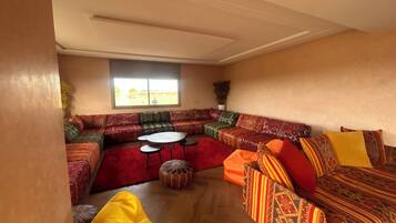 Ein geräumiges Wohnzimmer mit einer großen Eckcouch, einem Couchtisch und einem kleinen runden Tisch.