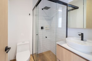 A modern bathroom with a glass-enclosed shower, a white toilet, and a sink with a mirror above it. - Myla - Loft LowF Near Centro Historico (Mexico City)