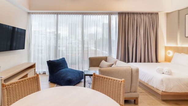 A hotel room with a bed, a sofa, a chair, a TV, and a dining table. - Myla - Loft LowF Near Centro Historico (Mexico City)