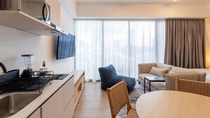 A modern kitchen with a built-in stove, a blender, and a flat-screen TV. There is a dining area with a round table and chairs, and a seating area with a sofa and armchairs. - Myla - Loft LowF Near Centro Historico (Mexico City)