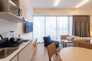 A modern kitchen with a built-in stove, a blender, and a flat-screen TV. There is a dining area with a round table and chairs, and a seating area with a sofa and armchairs. - Myla - Loft LowF Near Centro Historico (Mexico City)
