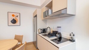 A compact kitchenette with a stove, kettle, and blender, a dining area with a table and chairs, and a wall-mounted microwave. - Myla - Loft LowF Near Centro Historico (Mexico City)