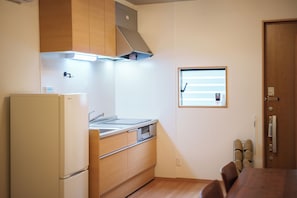 A compact kitchen with a refrigerator, stove, and wooden cabinets.