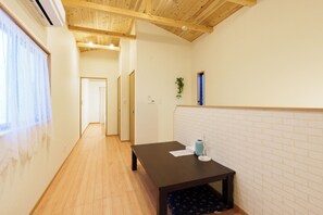 Een hal met houten vloer, een tafel met een vaas en papieren, en een muur met een baksteenmotief.
