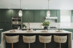 A modern kitchen with a central island, bar stools, and pendant lighting. - 4500sqft 6BR/7BA/9 Beds/6 Suites/PS5/Texas Hold’em (Rowland Heights)