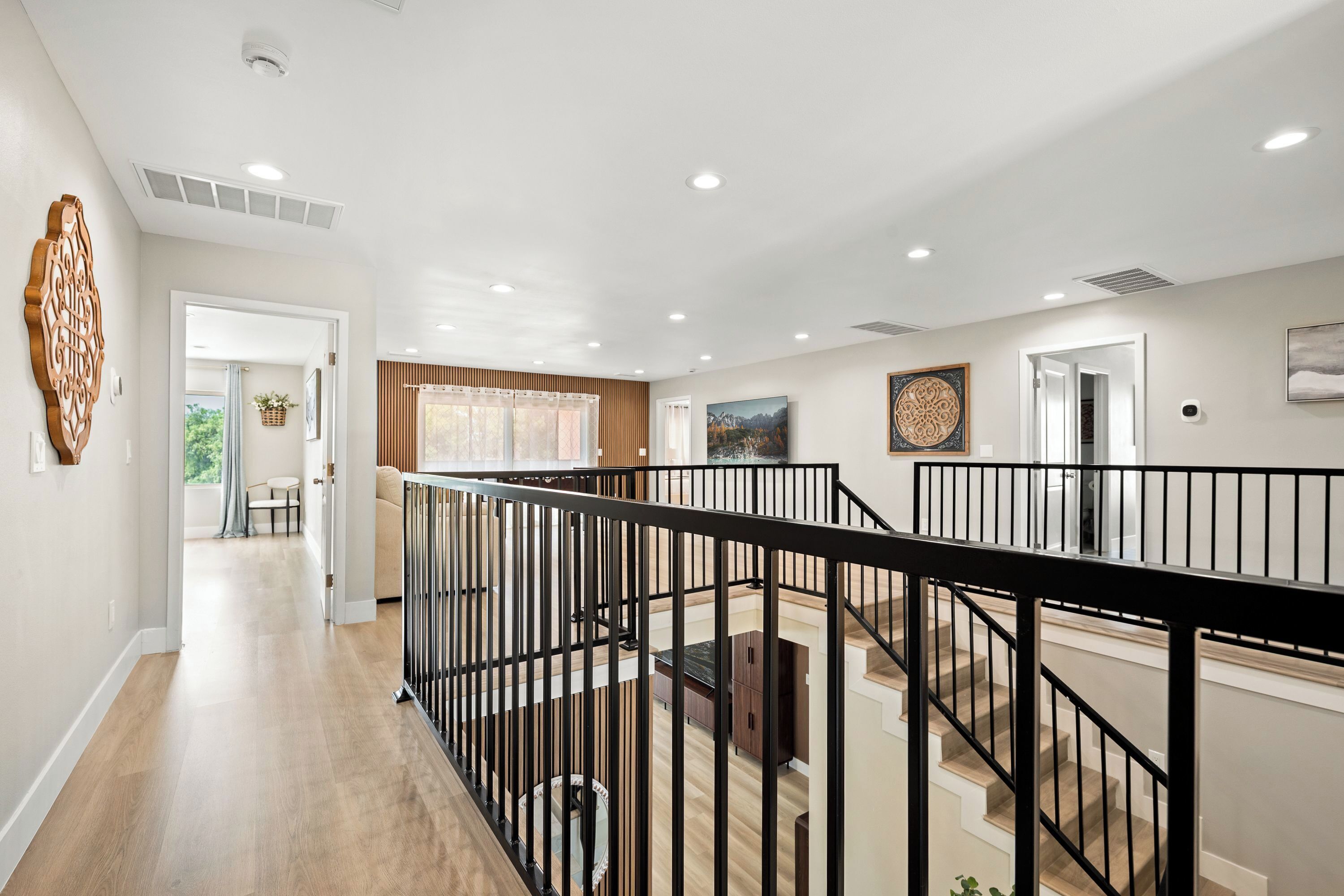 A spacious interior with a wooden floor, a black railing, and a staircase leading to an upper level.