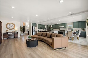 Un salon moderne avec un canapé aux lignes courbes, une table basse ronde et un coin repas comprenant une table et des chaises.