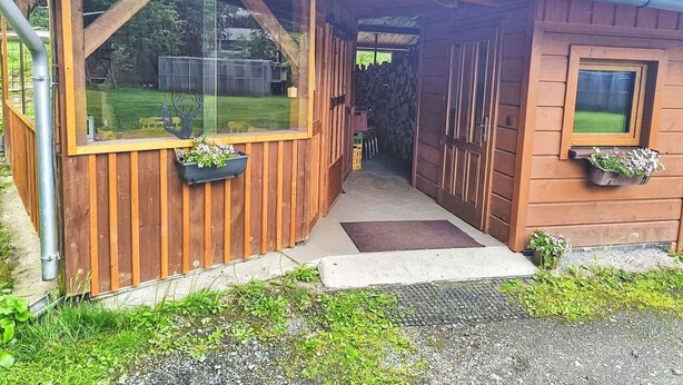 A wooden cabin with a covered porch, large windows, and flower boxes.