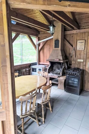 Una cocina rústica con un horno de piedra, sillas de madera y una mesa de comedor.