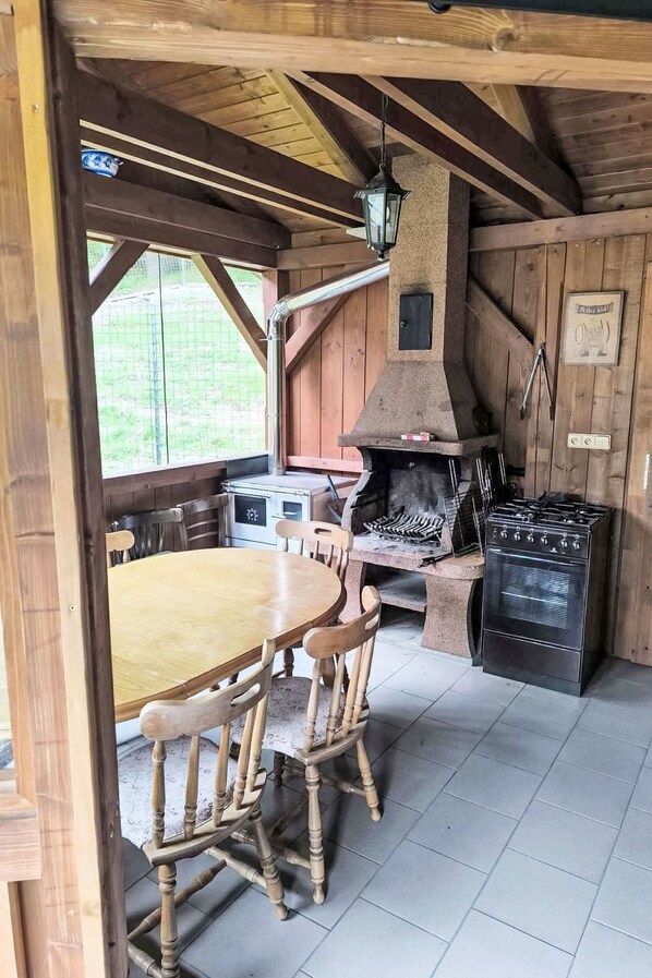 Una cocina rústica con un horno de piedra, sillas de madera y una mesa de comedor.