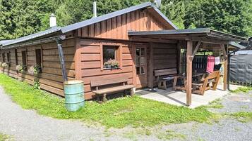 Une cabane en bois avec une véranda, une fenêtre ornée de fleurs et un banc.