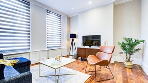 A modern living room with a sofa, coffee table, and a television. - Hybridresi Battersea - Battersea Park Road (London)